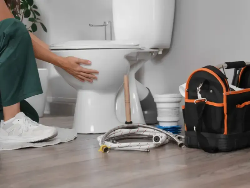 Plumber steadying a newly set toilet bowl during a toilet installation in Kirkland, WA