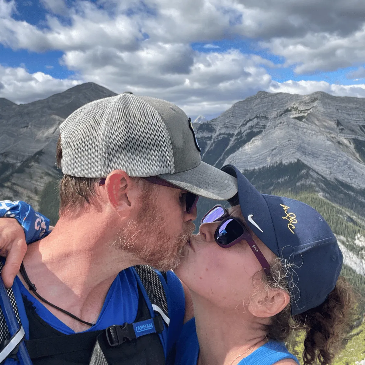 Meredith and Craig | The Unstoppable Team kissing on a mountain summit with a 200% Marriage