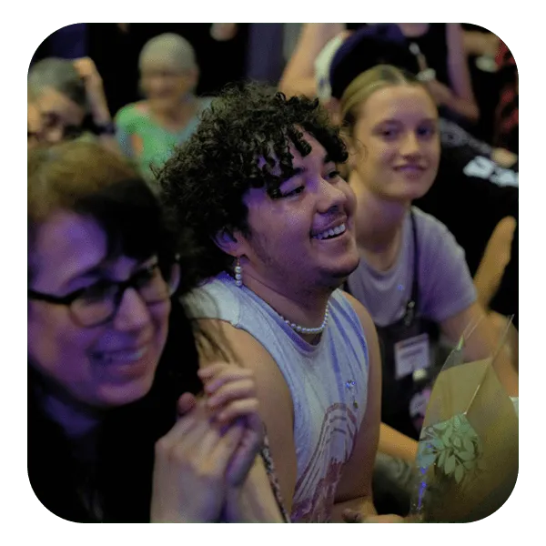 A gathering of people in a room, featuring one individual with a bright smile, enhancing the overall cheerful ambiance.