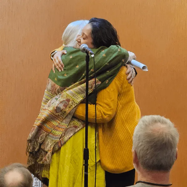 A woman embraces another woman warmly, showcasing a moment of affection and support between them.