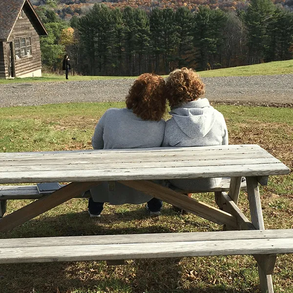 Two individuals seated at a picnic table, enjoying a serene outdoor setting together.