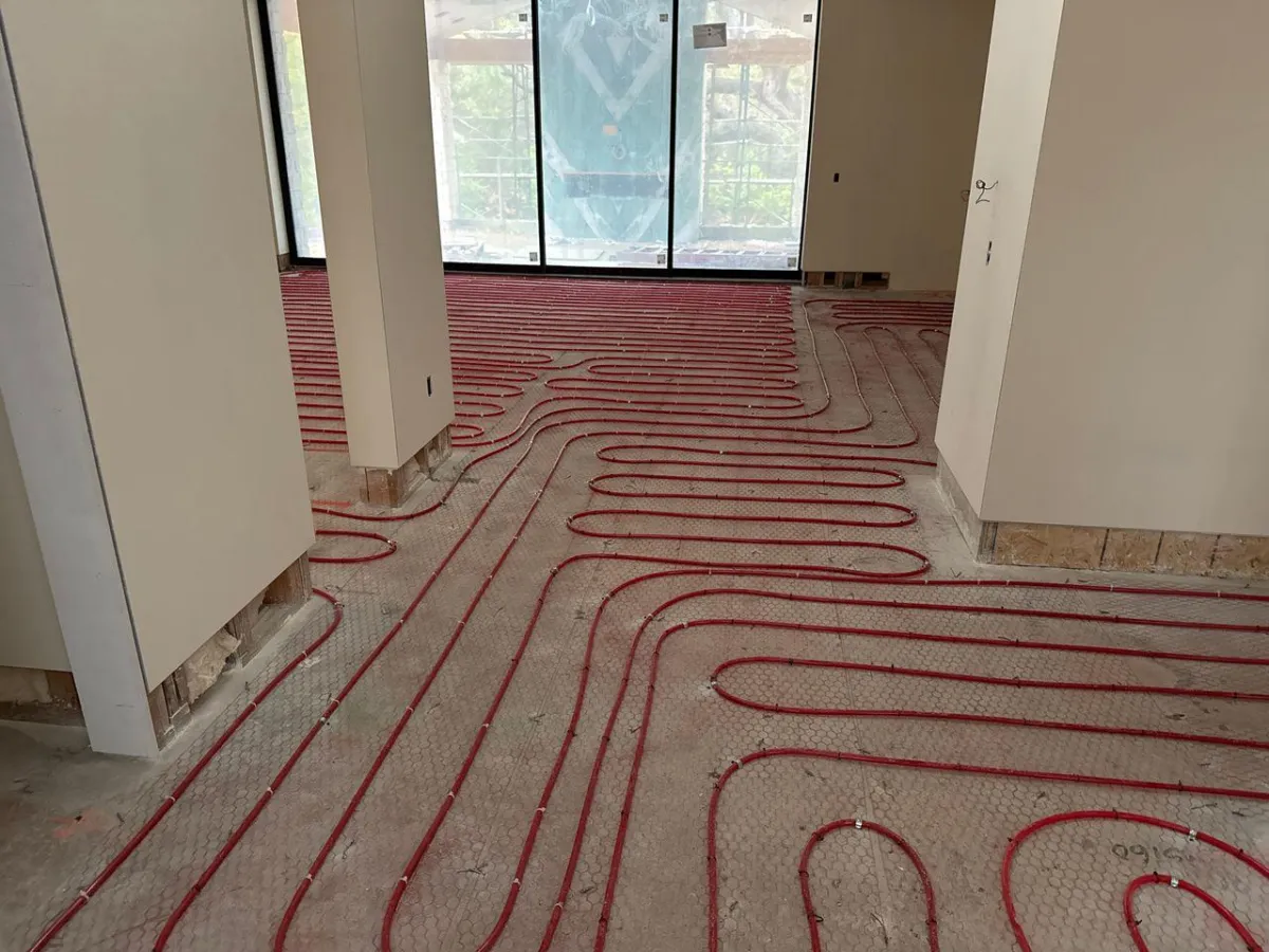 Radiant floor heating installation in progress at a residential new-build in Southern California, featuring precision-laid red PEX tubing over insulated subfloor for energy-efficient, whole-home heating.