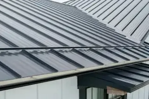 Close-up of dark standing seam metal roof panels meeting at a ridge junction