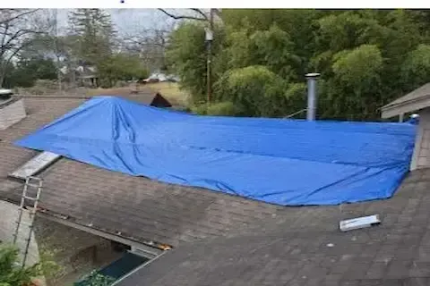 Blue emergency tarp installed over storm-damaged roof in Coon Rapids by Coon Rapids Roofing Pros