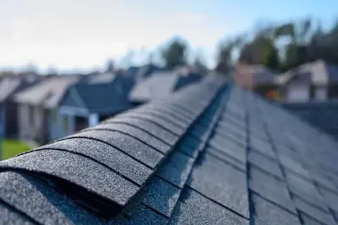 Close-up of dark asphalt shingles along a freshly installed roof ridge