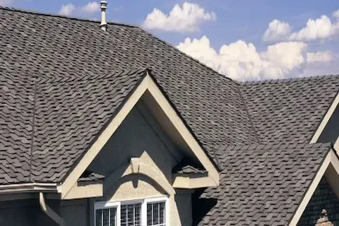 Gray architectural shingles covering peaked roof sections with dormer windows