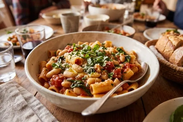 A bowl of tomato and white bean pasta, illustrating 15-minute family meals made from an essential pantry staples list.