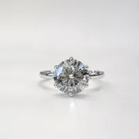 A classic solitaire engagement ring featuring a round brilliant-cut diamond set on a sleek white metal band. Photographed from the front against a soft neutral background, the design highlights the diamond's sparkle, symmetry, and timeless elegance.
