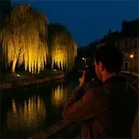 Photographe de nuit sur les bords de l’Iton à Évreux, avec des saules pleureurs illuminés par des éclairages urbains