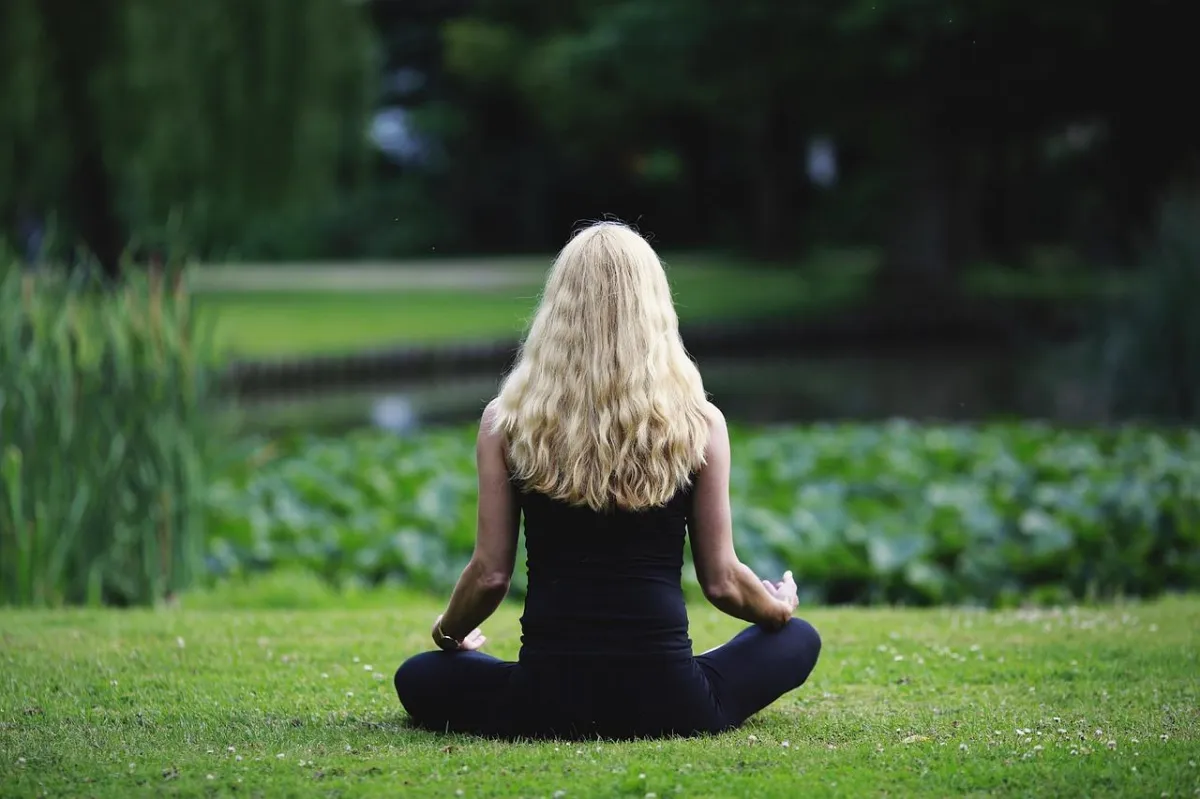 woman meditating on green grass