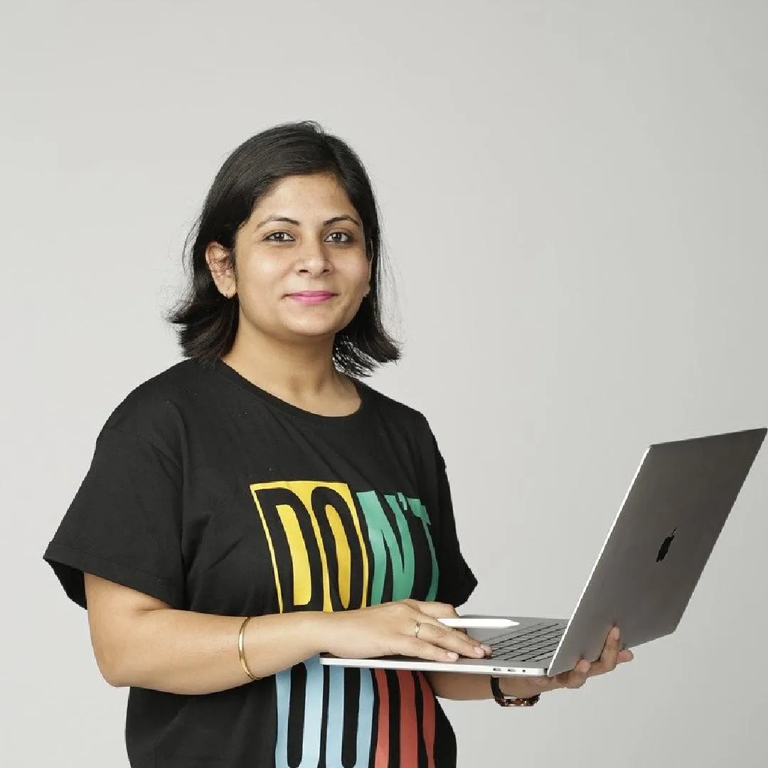 casually dressed woman business owner smiling while holding an open laptop