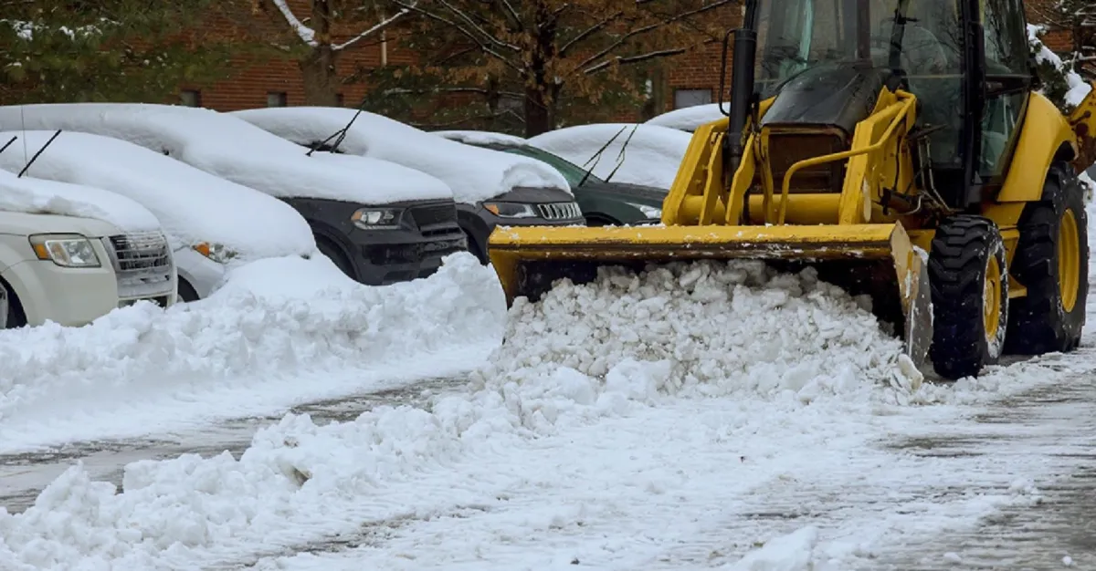 A bull dozer removing heavy snow from a parking lot