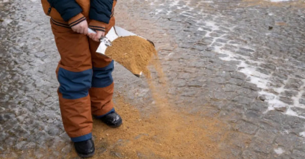 A man sprinkling sand and gravel on the road to prevent black ice.