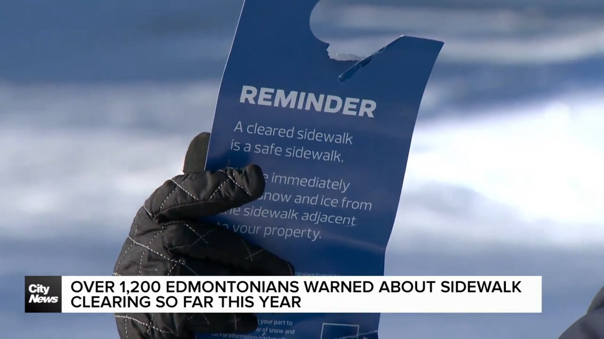 A person holding a snow removal reminder notice by the city of Edmonton.
