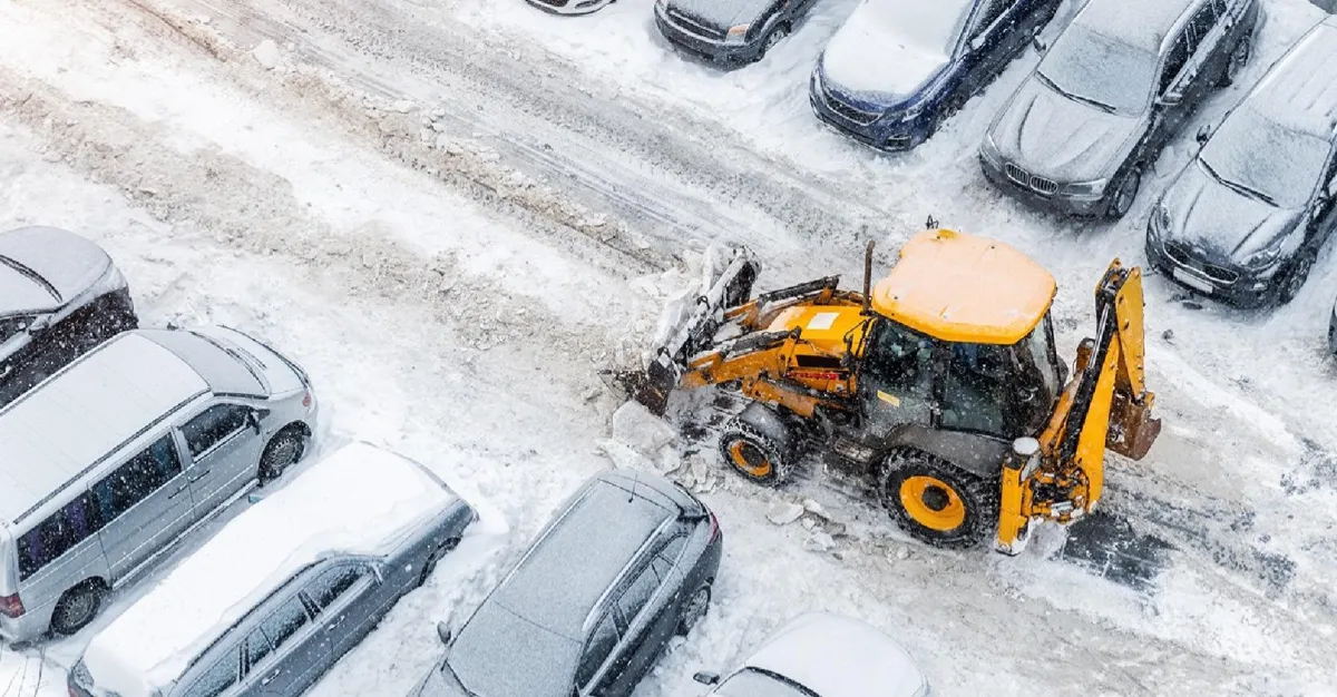 A man clearing snow from the side walk of a house. 