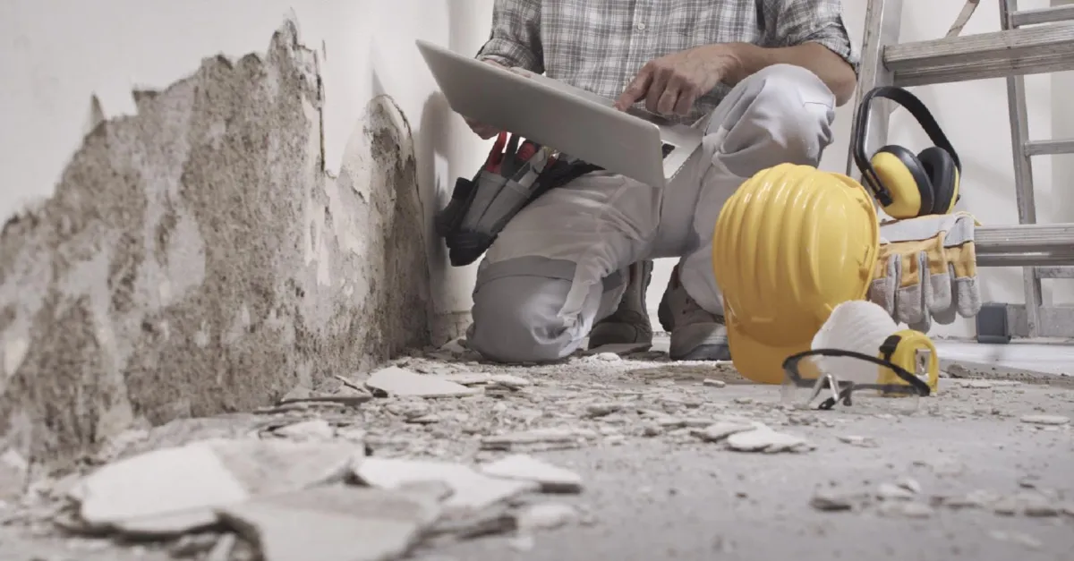 A professional contractor analysing the damage done on the wall by water.