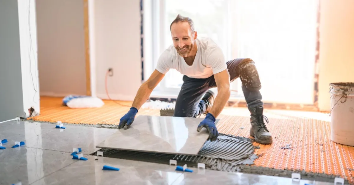A contractor applying tiles on the floor.
