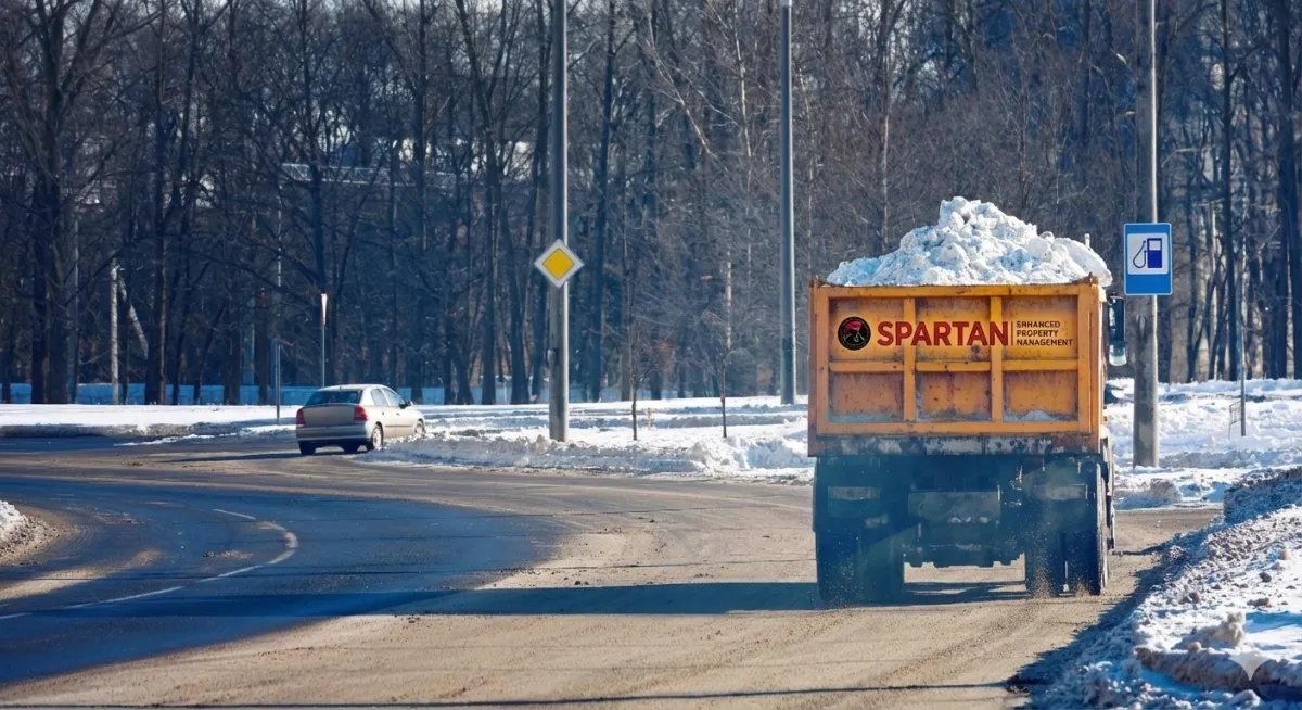 A red snow removal trucks loaded with snow in the middle of a road lot full of snow.