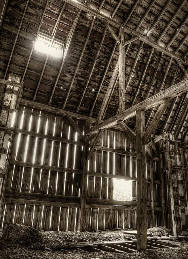 Old barn with light streaming through the cracks and windows to brighten the dim space