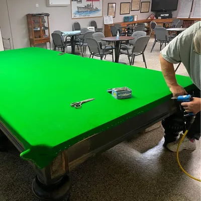 man recovering pool table felt