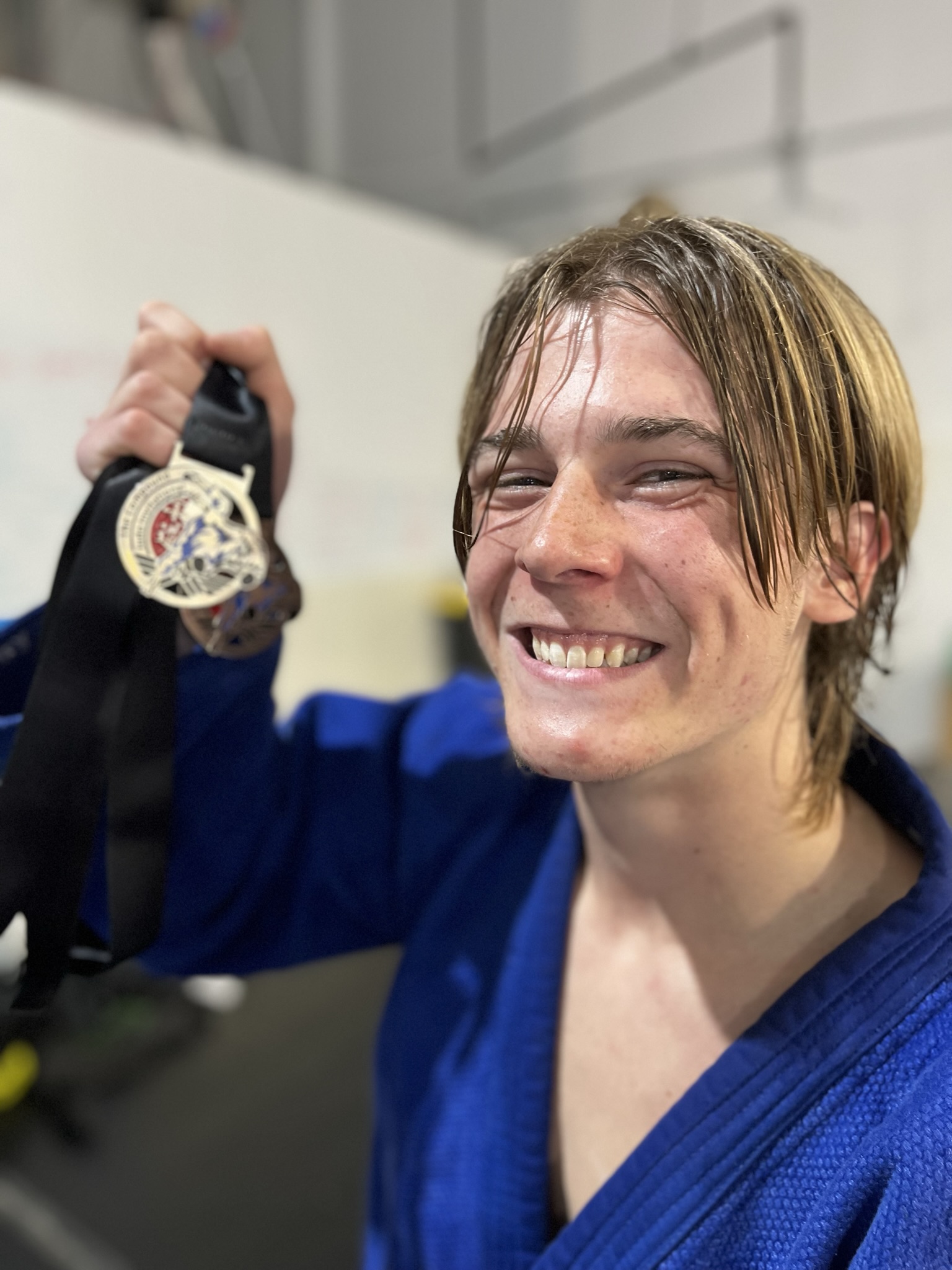 Youg Man showing medals from a Jiu Jitsu, Judo, Martial Arts competition