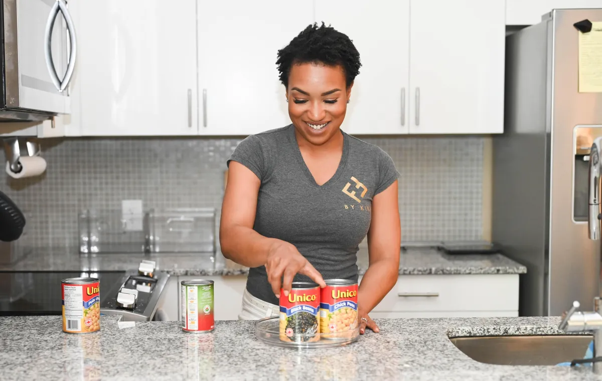 A professional organizer in a kitchen organizing cans on a lazy susan.