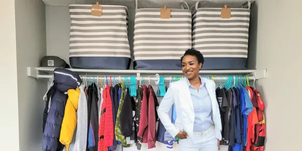 A professional organizer posing in front of an organized boy's closet 