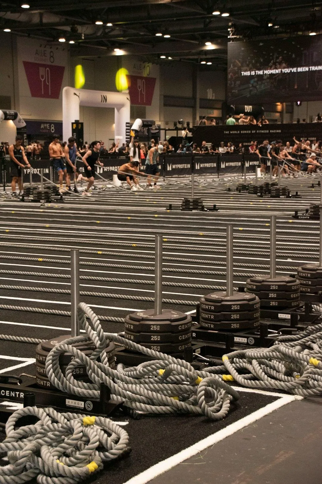 Athlètes en entraînement hybride alternant course, rameur, sled push et exercices fonctionnels dans un centre d’entraînement moderne