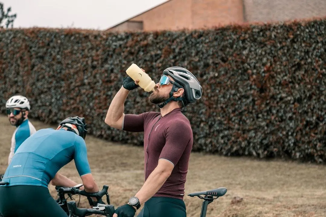 Personne active qui s’hydrate et mange une collation énergétique après un entraînement fonctionnel ou une sortie de course.