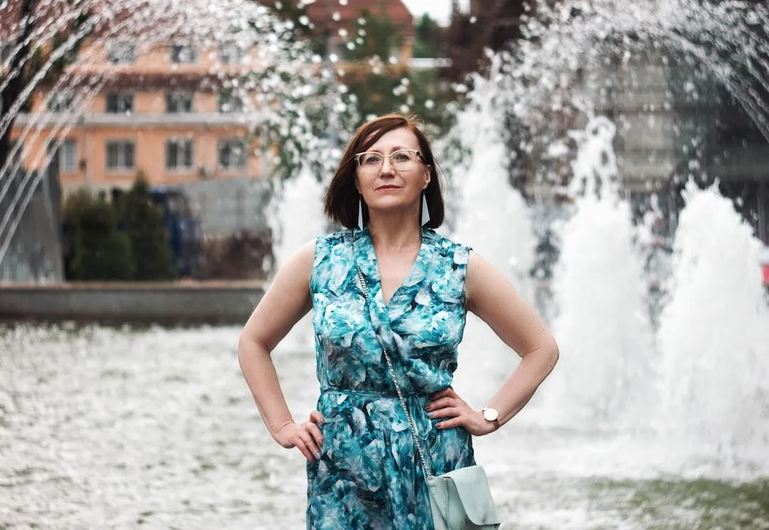 confident middle-aged white woman with brown hair in blue dress standing in her own value