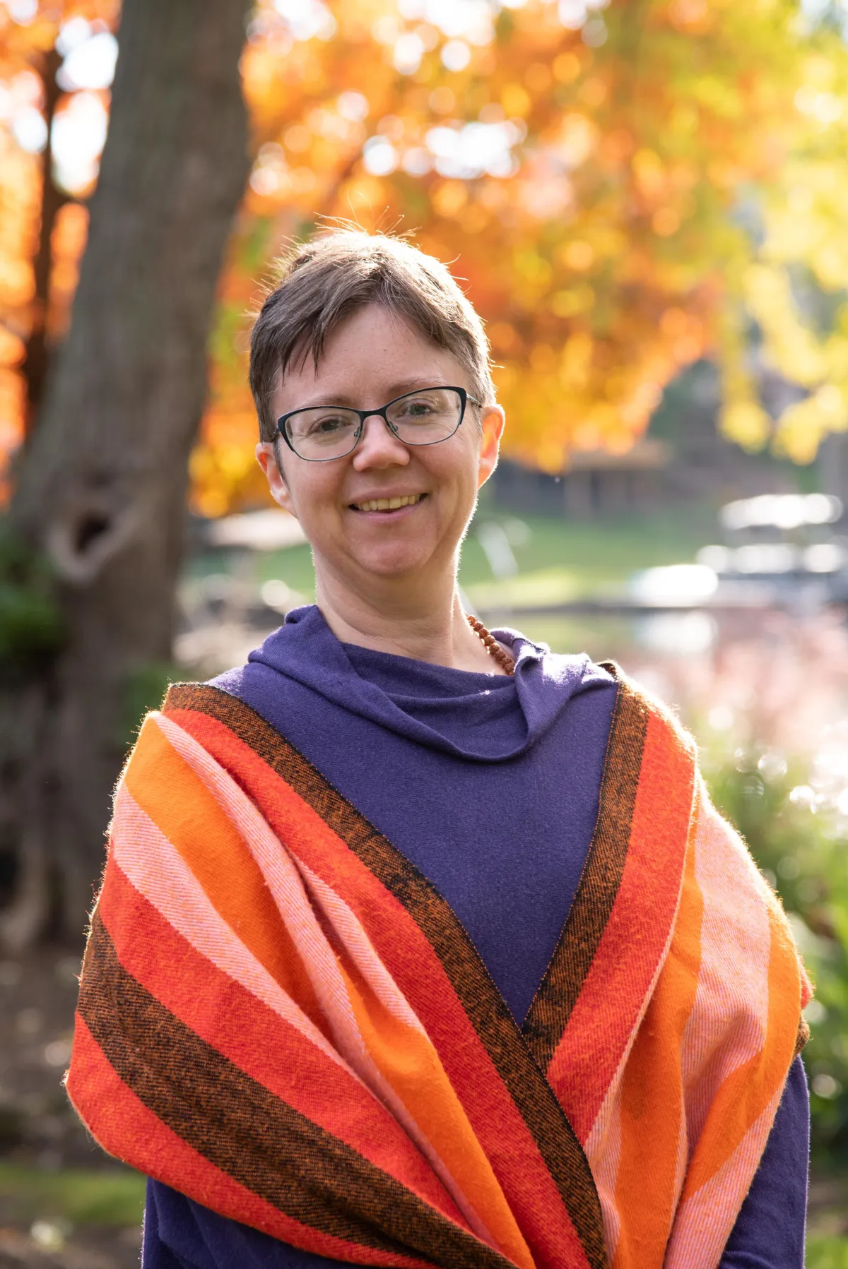 White woman with short hair wearing purple sweater and orange scarf