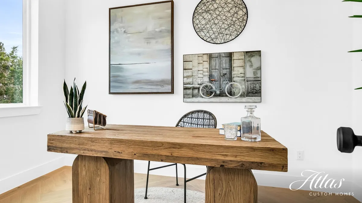 Curated home office design selections — reclaimed wood desk, framed art, and finish details in an Atlas Custom Homes build
