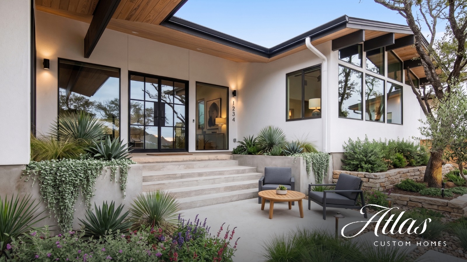Front entry of a completed Atlas Custom Homes luxury build in Central Texas, with steel-framed glass doors, cedar soffits, and native Hill Country landscaping