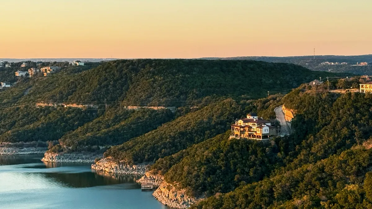 Golden-hour aerial view of a Hill Country estate on a limestone bluff above Lake Travis, Texas