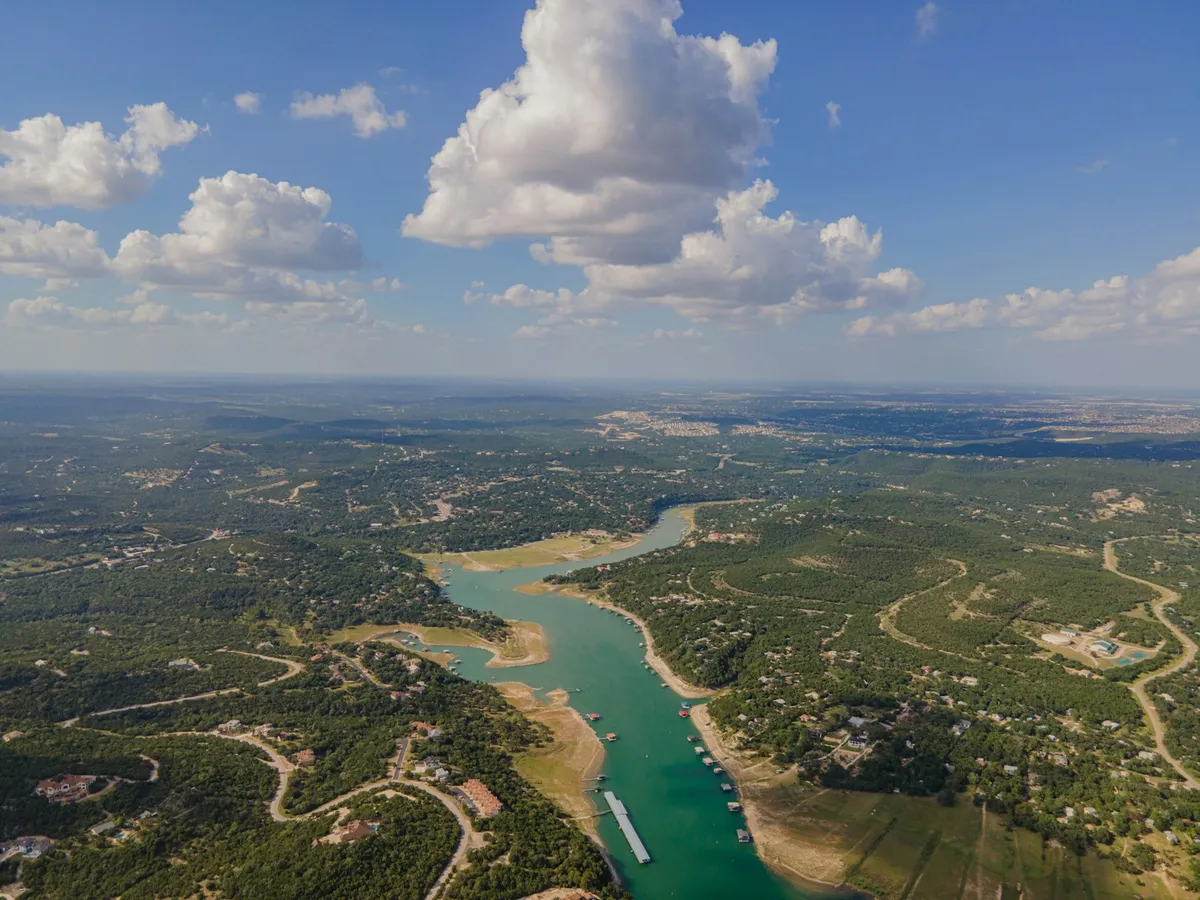 Aerial view of a Texas Hill Country lake inlet lined with wooded home sites and waterfront properties near Lakeway