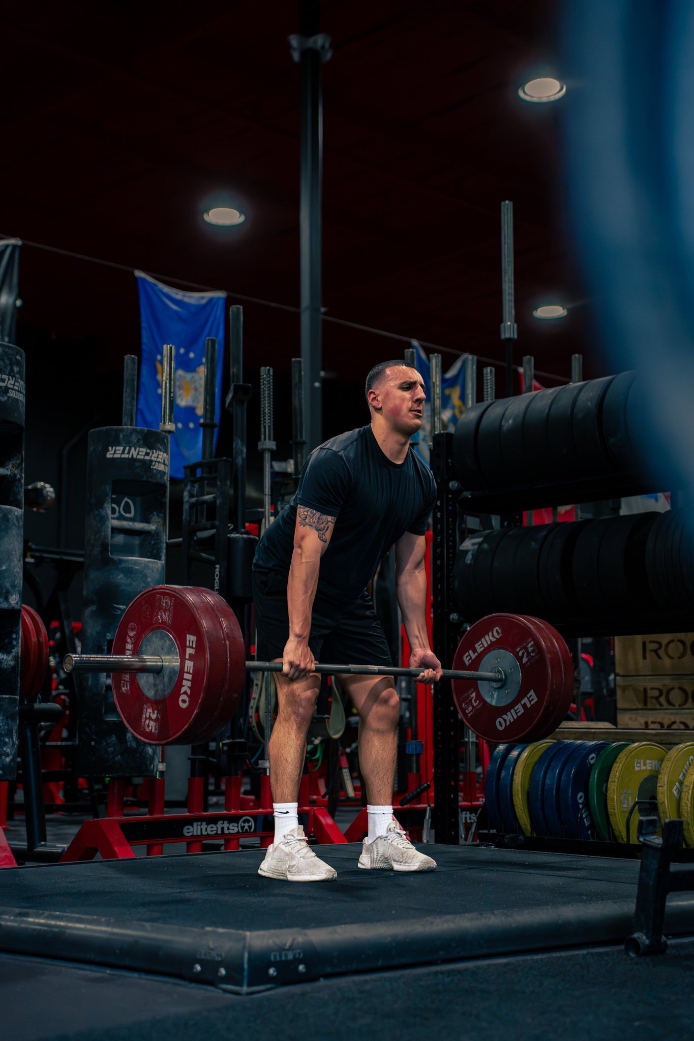 Determined adult executing barbell deadlift with clean biomechanics in gritty studio