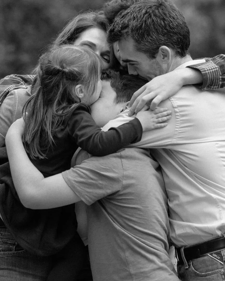 Happy Christian family hugging together outdoors, showing love, unity, and the joy of parenthood in a strong and faith-centered home.