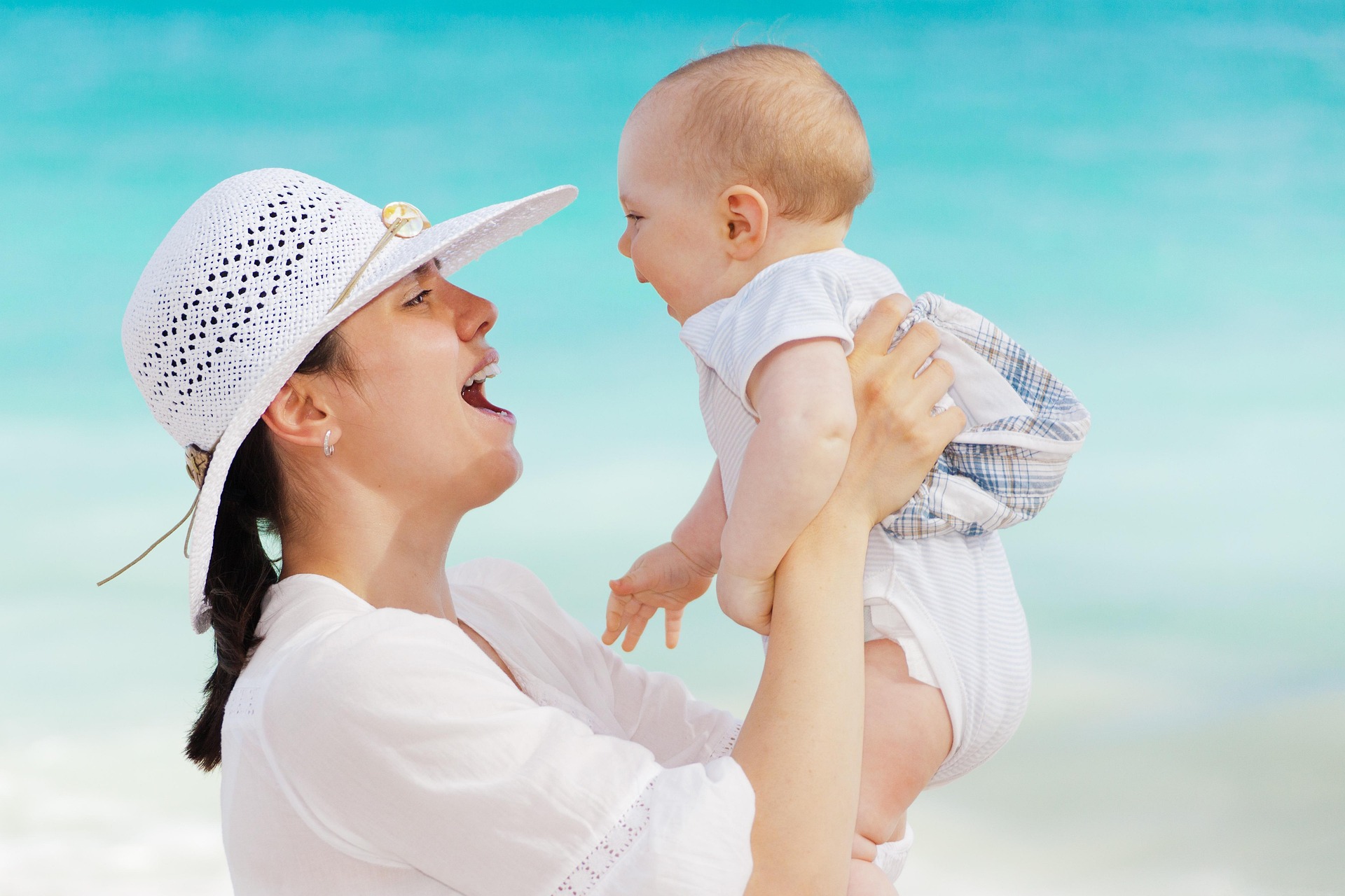 Mother holding her baby outdoors by the beach, expressing joy, love, bonding, and the beauty of motherhood.