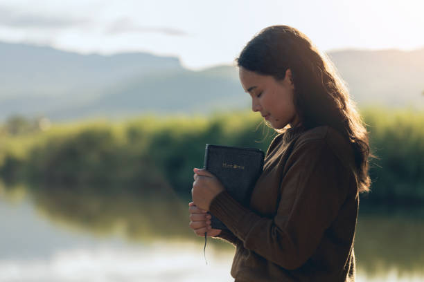 Young Christian woman holding a Bible outdoors during a difficult season, trusting God for strength, comfort, peace, and hope through faith. SEO Meta Description: