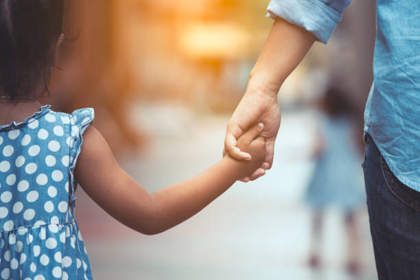 Parent gently holding a young child's hand, symbolizing trust, love, security, and strong parent-child relationships built through care, consistency, and biblical values.