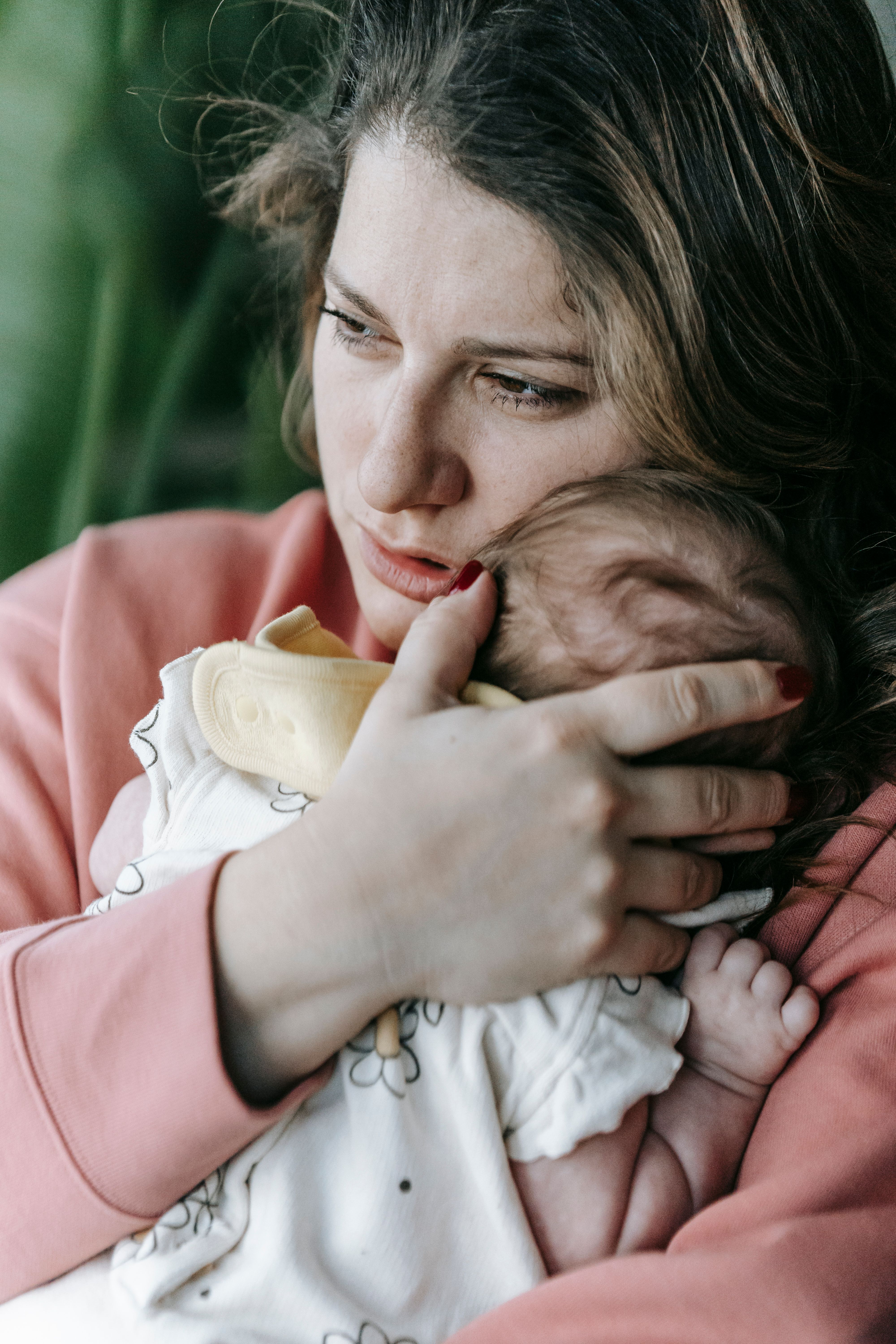 Concerned mother gently holding her infant baby while looking thoughtful and worried, representing motherhood challenges, parental anxiety, emotional support, faith during difficult times, and trusting God through uncertainty.