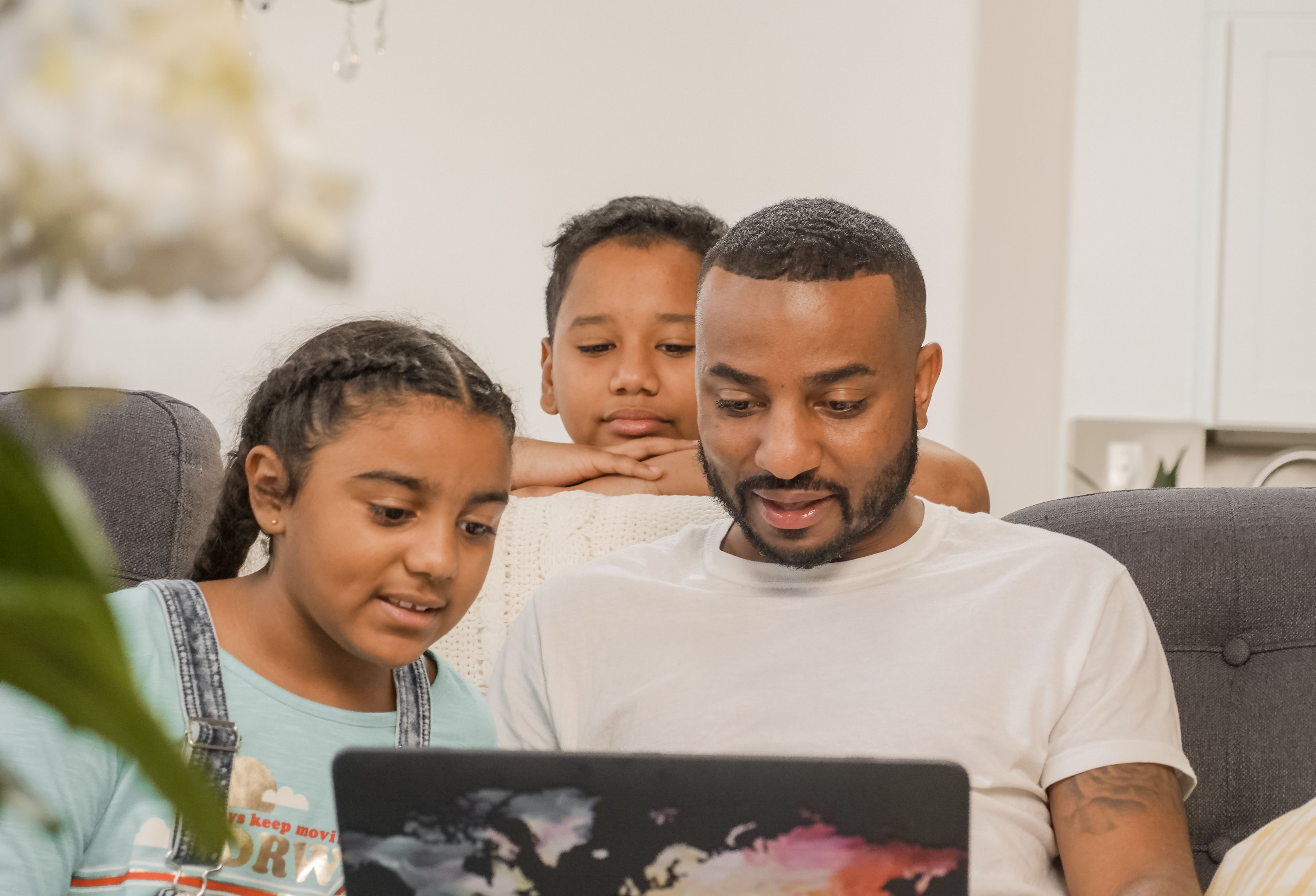 Father sitting with his son and daughter while using a laptop together at home, illustrating quality family time, intentional parenting, building strong relationships, Christian family values, and investing in children through love, guidance, and shared learning.