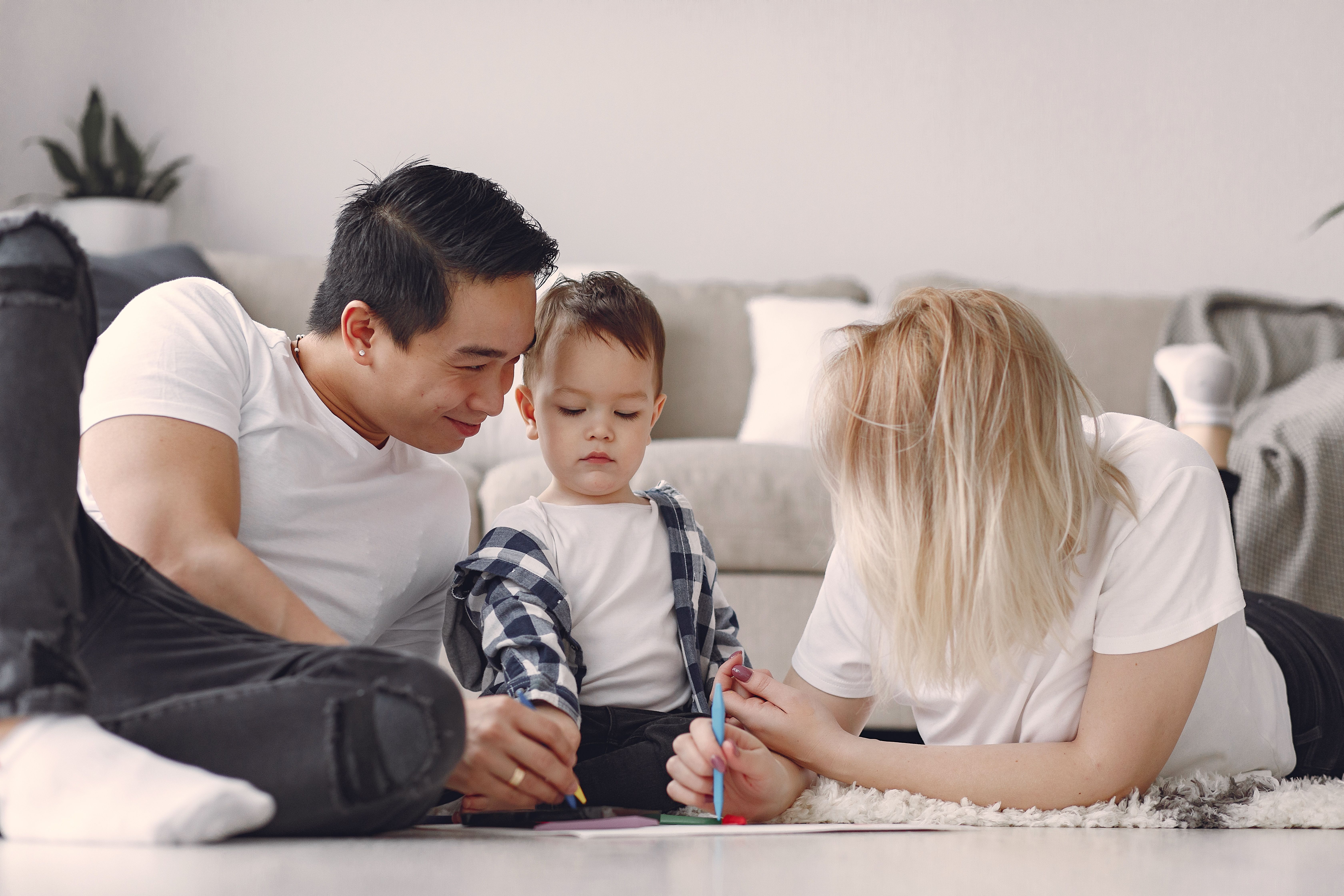 Mother and father drawing with their toddler on the living room floor, creating meaningful family moments through patience, love, play, and Christ-centered parenting.