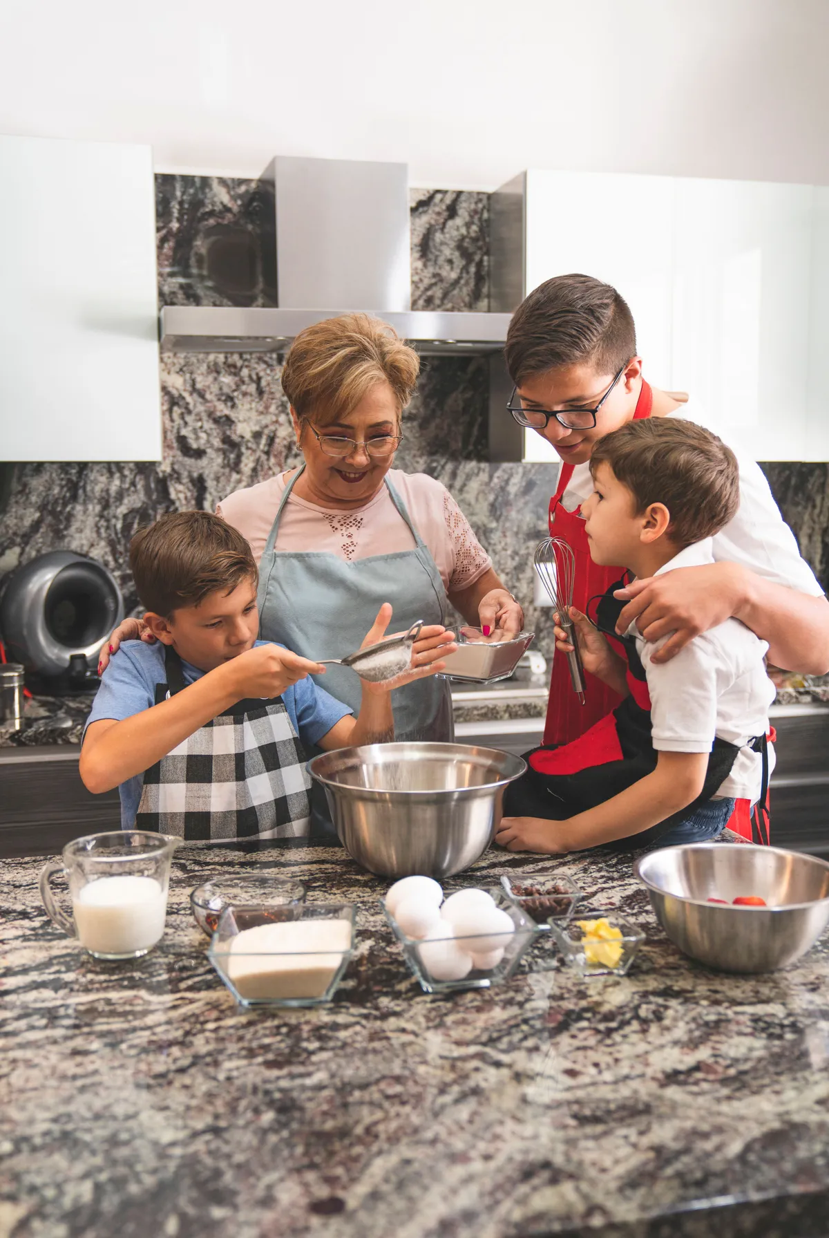 A grandmother and father teaching children how to bake together in a family kitchen, demonstrating how cooking with children builds teamwork, responsibility, food preparation skills, and meaningful family bonds.