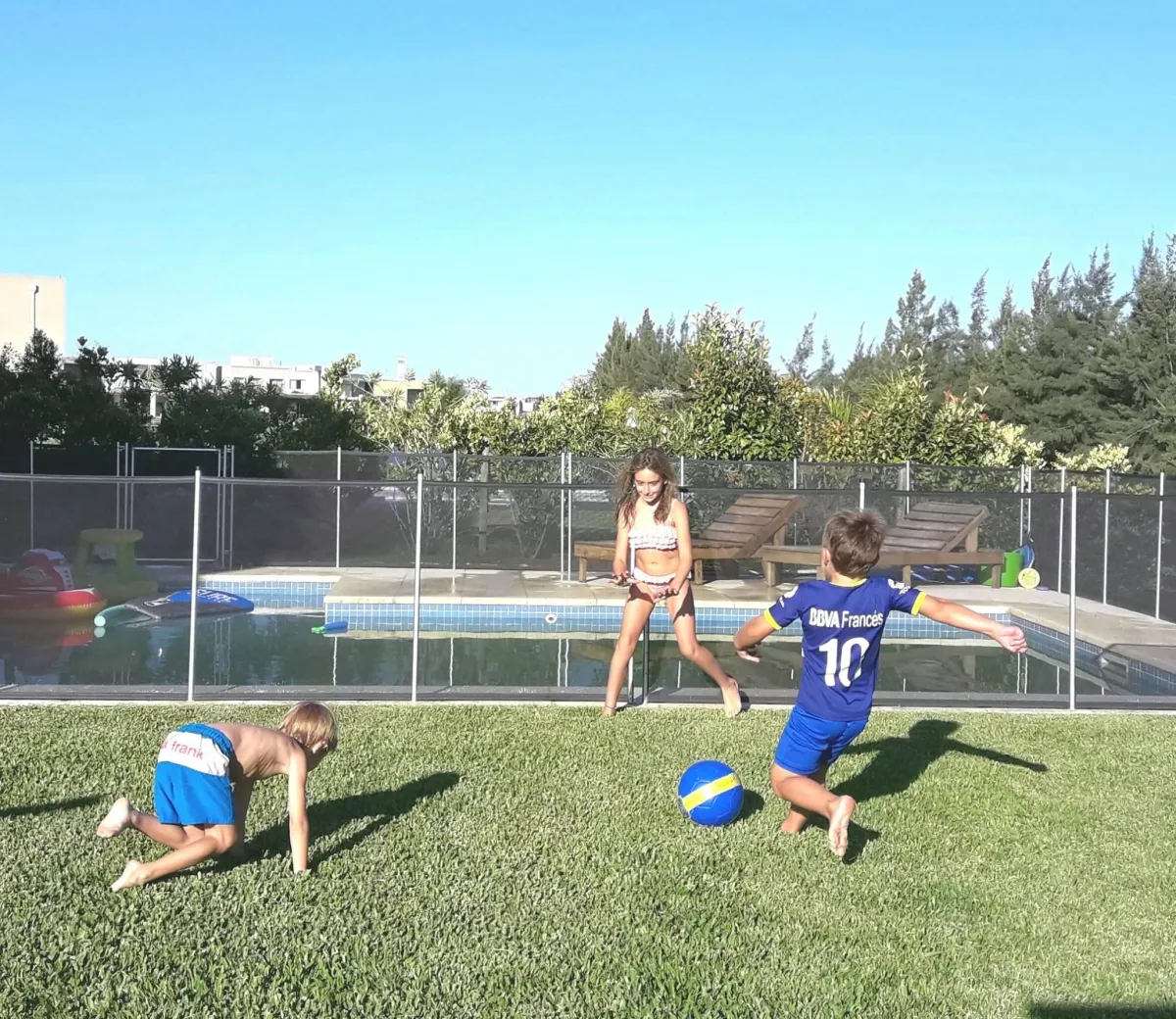 Niños jugando al aire libre junto a una piscina protegida con vallas de seguridad Babysecur, garantizando un entorno seguro y divertido.