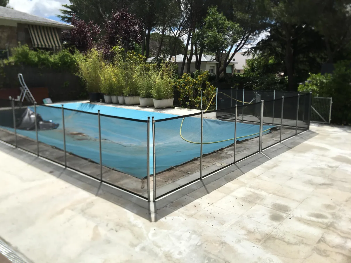 Piscina cubierta con lona protectora y rodeada por vallas de seguridad Babysecur, asegurando la protección infantil y evitando accidentes.