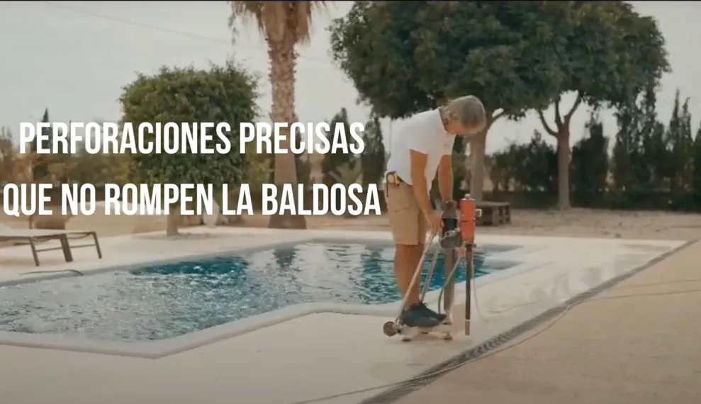 Instalador realizando perforaciones precisas junto a una piscina para instalar vallas Babysecur, garantizando que no se dañen las baldosas.