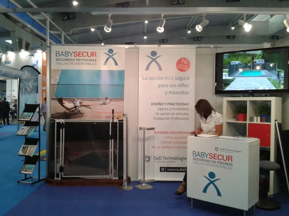 Stand de Babysecur en una feria, destacando sus vallas desmontables de seguridad para piscinas con información detallada y atención personalizada.