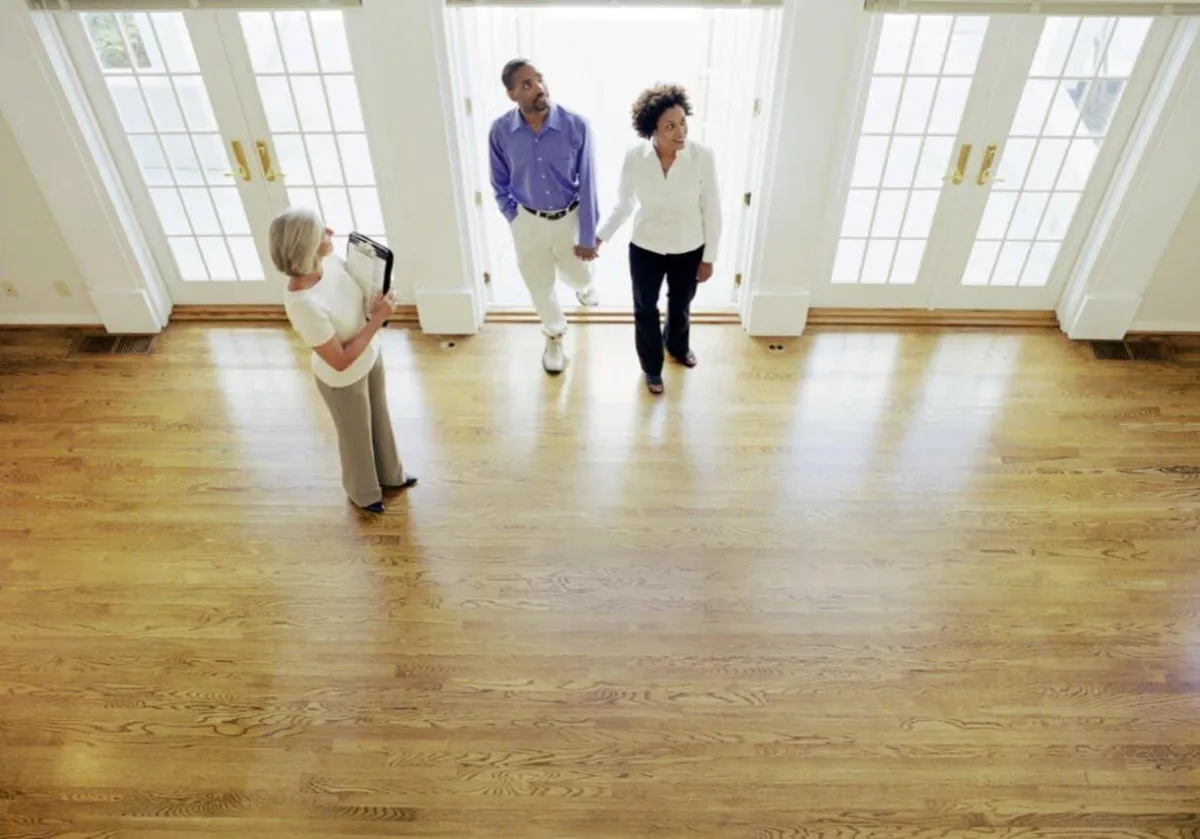 A bright and spotless room with polished hardwood floors, showcasing a clean and refreshed space. Three individuals, likely clients or real estate professionals, are inspecting the area, reflecting the exceptional cleaning standards provided by **True Cleaning Experts**. The gleaming floors and natural light emphasize the team's ability to deliver high-quality cleaning results for move-in and post-construction services.