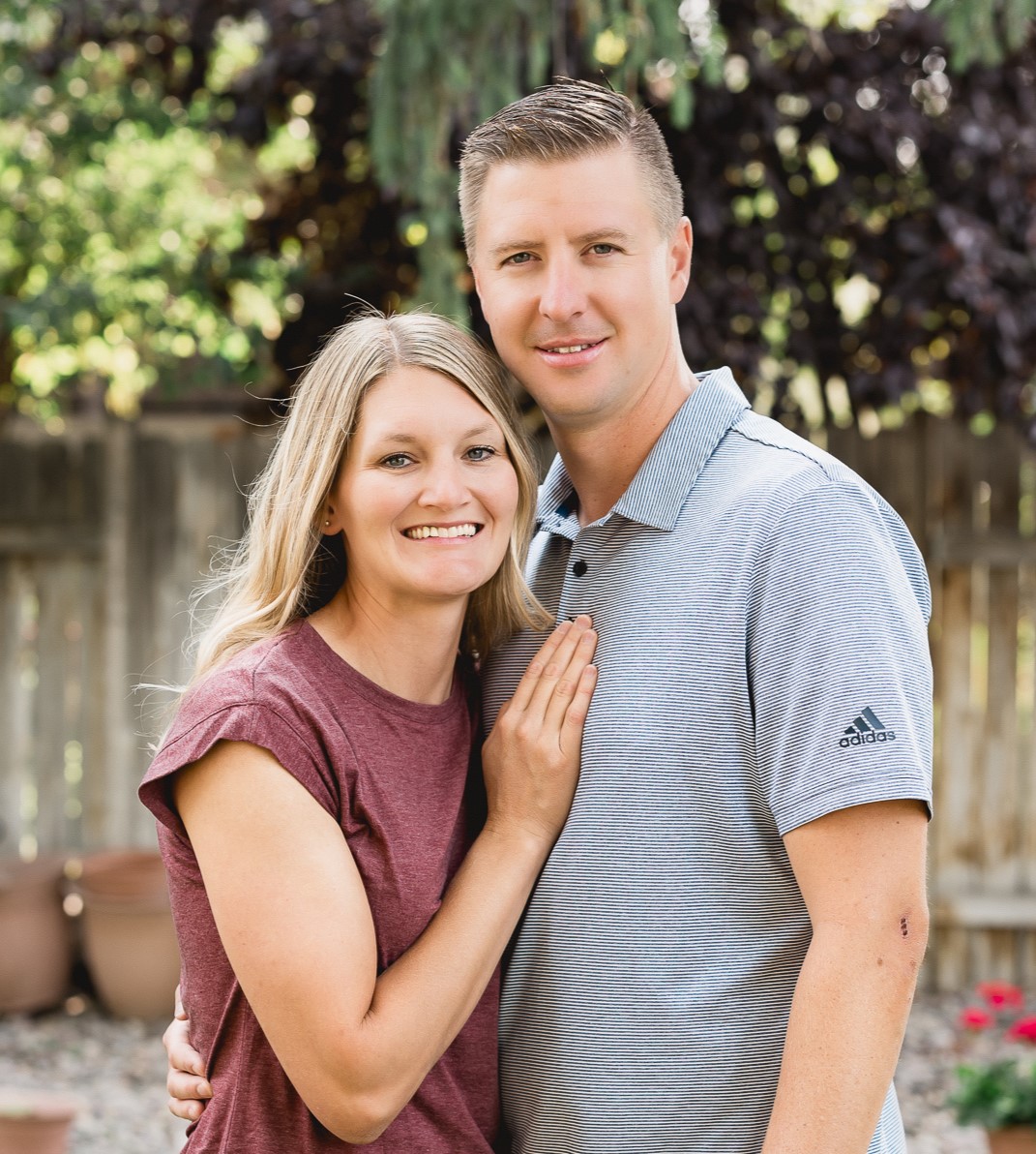 Three founders, a man and a woman in their 30s, sitting together on a sunlit porch, both wearing faith-themed shirts. They hold hands, smiling with gratitude, a car key resting between them, symbolizing their survival. The scene radiates hope and unity.